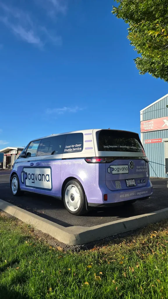 A purple van with branding parks beside a building under a clear blue sky