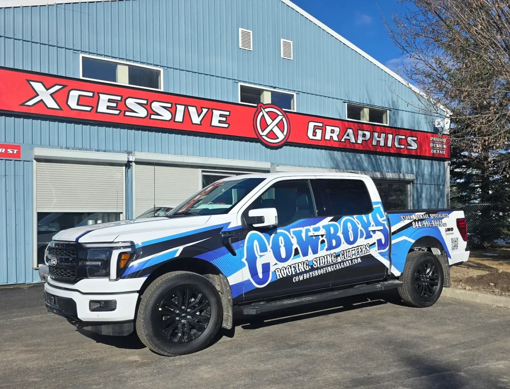 Custom stickers decorate a branded truck parked by an Xcessive Graphics sign