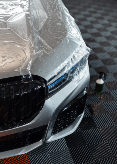 Sleek silver car covered in paint protection film shines in a bright garage