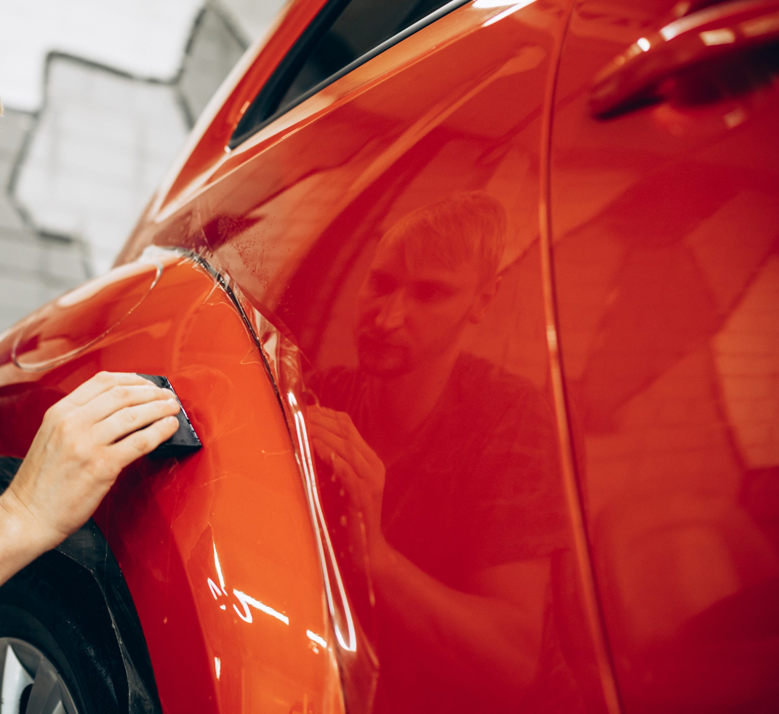 Decals graphics enhance the shiny red car as a person polishes its surface