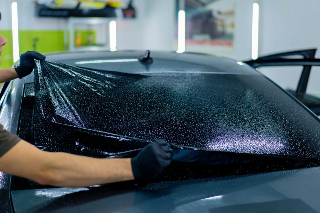 Window tinting Dewinton being applied to a car window for enhanced privacy and style